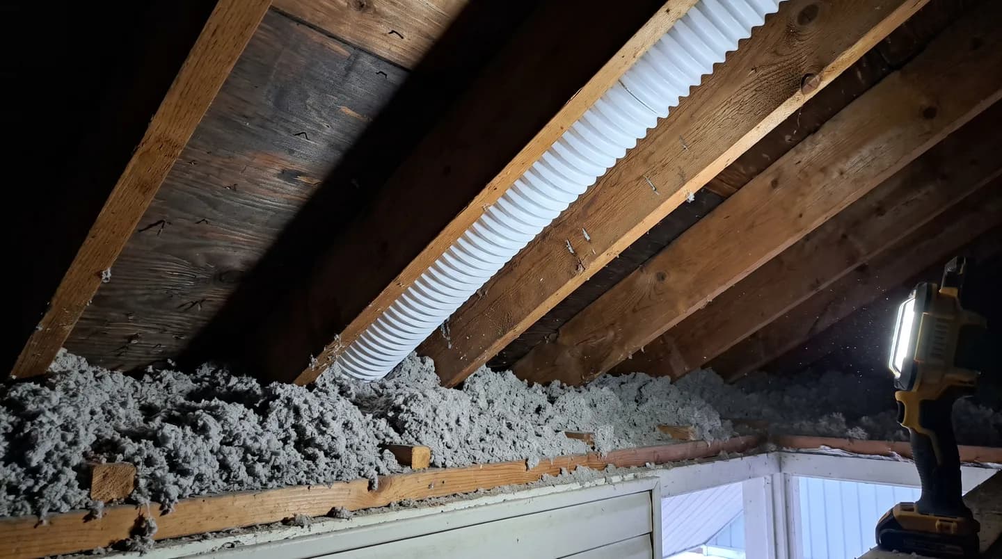 Attic baffle holding an open air channel above blown insulation at the eave of an Ontario home in winter