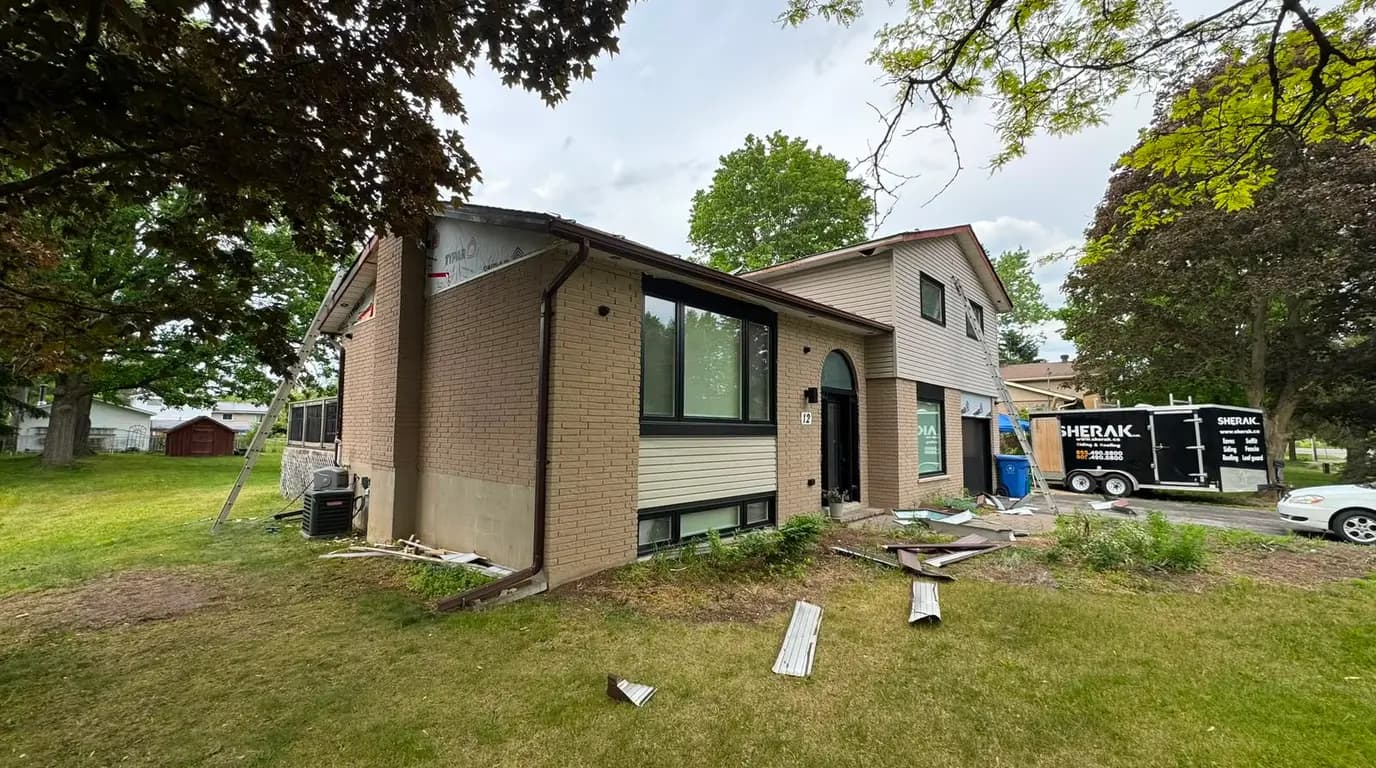 The Sherak trailer parked at the side of the house with old cladding stacked on the lawn during the strip-out
