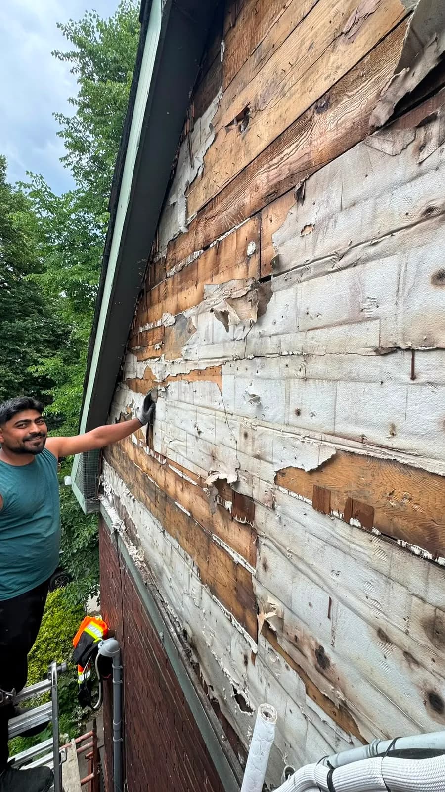 The old wall surface after the strip-out: wood boards, torn sheathing paper and old fastener holes