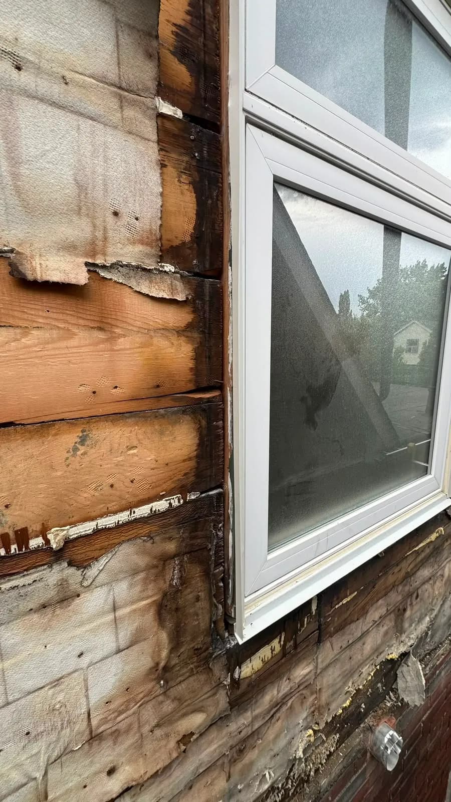 Close-up of the original board sheathing beside a window after the old cladding came off