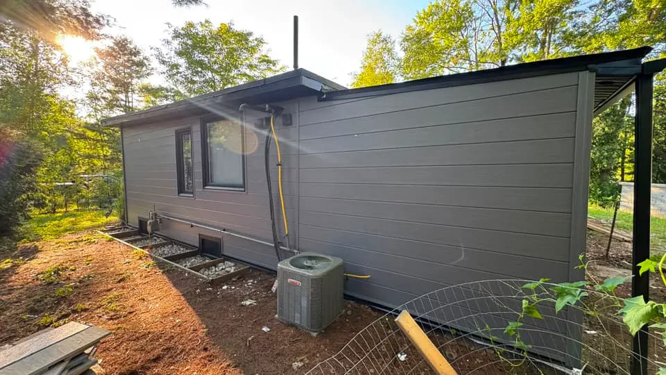 Long elevation of grey engineered wood plank siding with a black drip edge and fascia