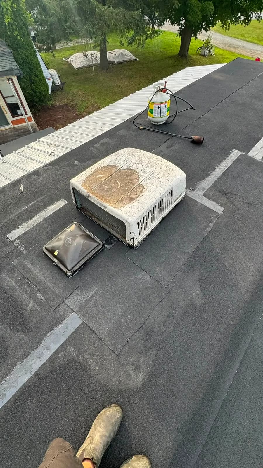 New membrane carried up around the base of the rooftop air conditioner and the roof vent, with extra strips at the corners