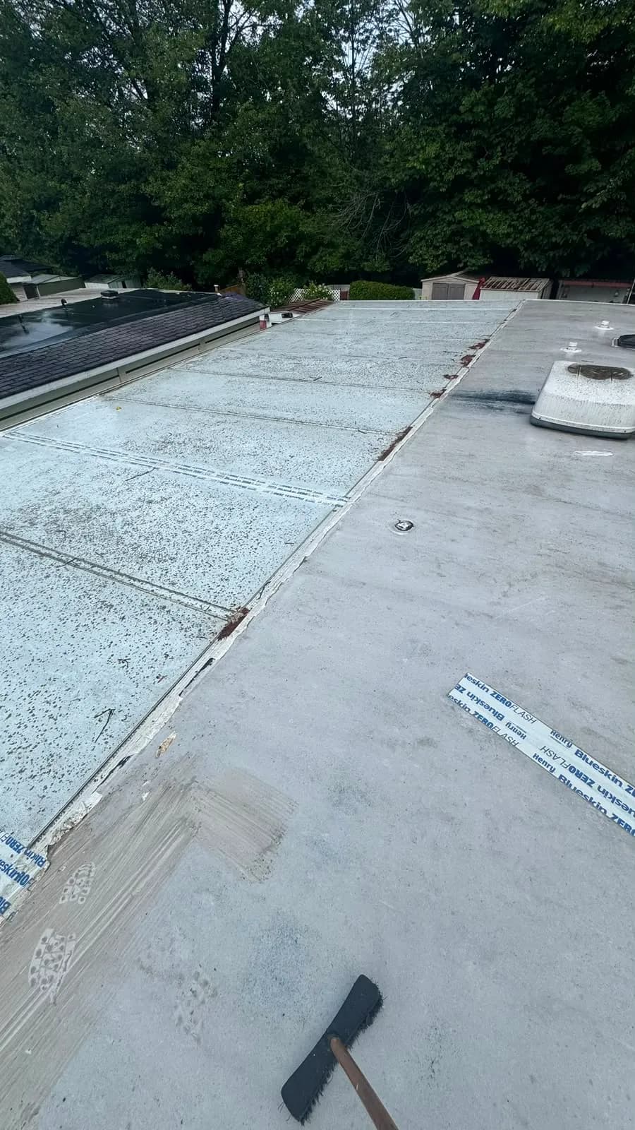 The old white-coated roof before the work, with years of patched seams and the rooftop air conditioner