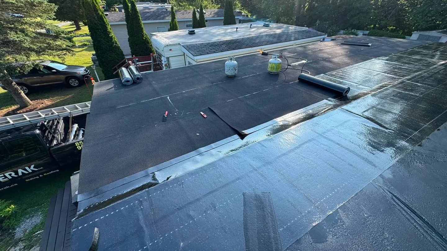 First courses of the new membrane rolled out, with membrane rolls and propane cylinders for the torches on the roof