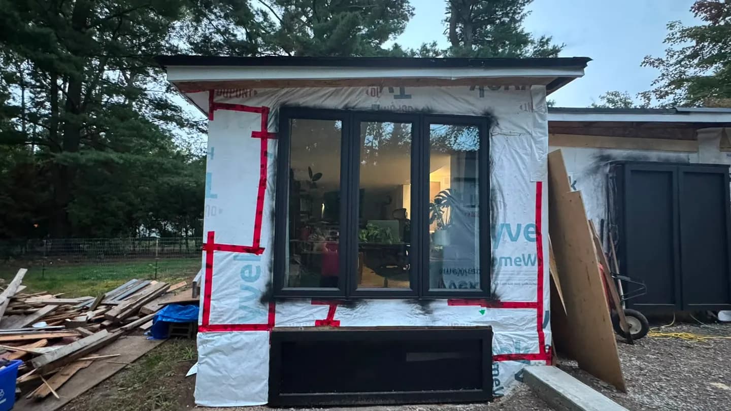 Window opening wrapped in Tyvek with red sheathing tape sealing the wrap around the frame