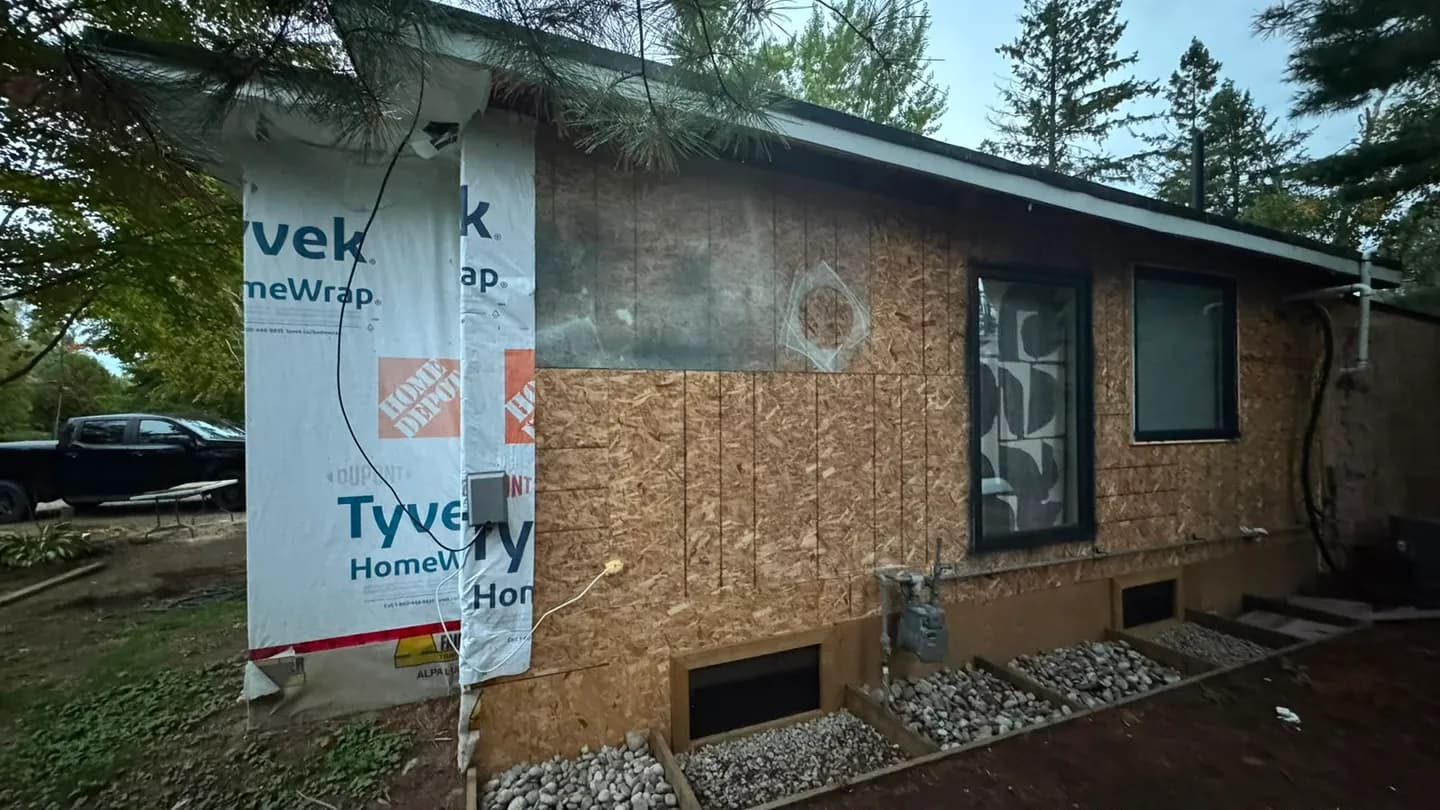 End wall with new OSB sheathing let in beside the old, and Tyvek starting at the corner