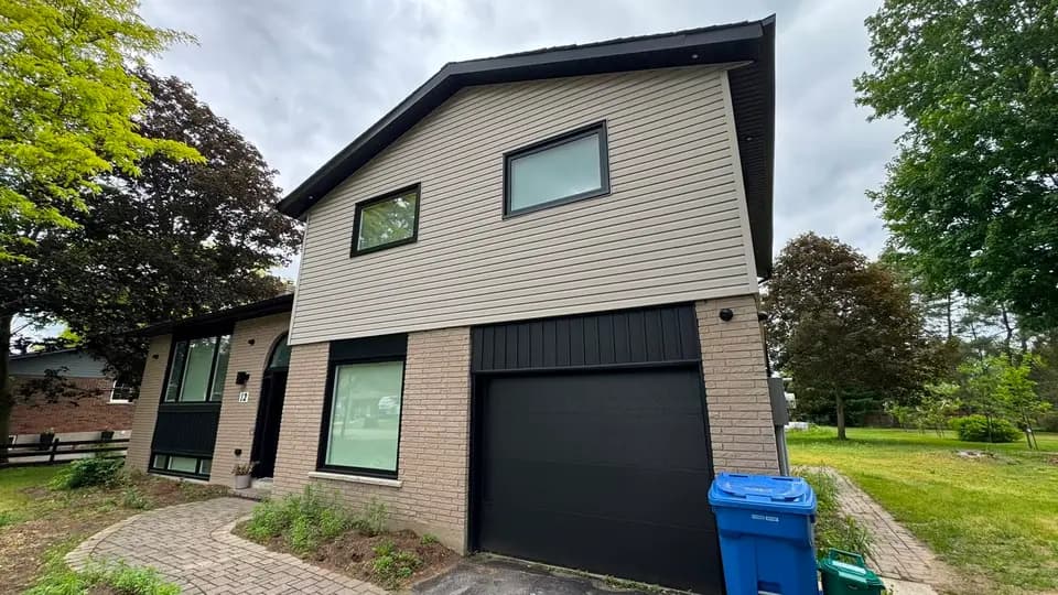 Finished garage elevation in Bradford clad in new horizontal siding with black fascia and a black garage door