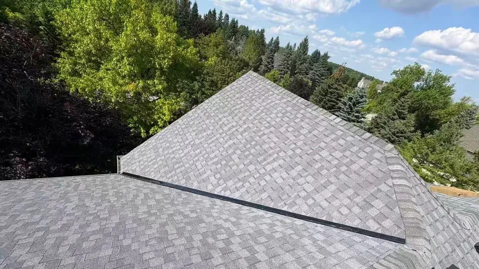 Finished architectural asphalt shingle roof on a wide hip-roofed home surrounded by mature trees, Stouffville