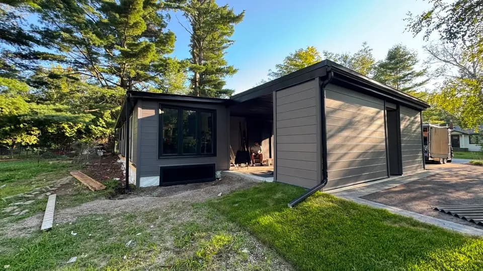 Single-storey home reclad in dark plank siding with black fascia and a new eavestrough line, Jackson's Point