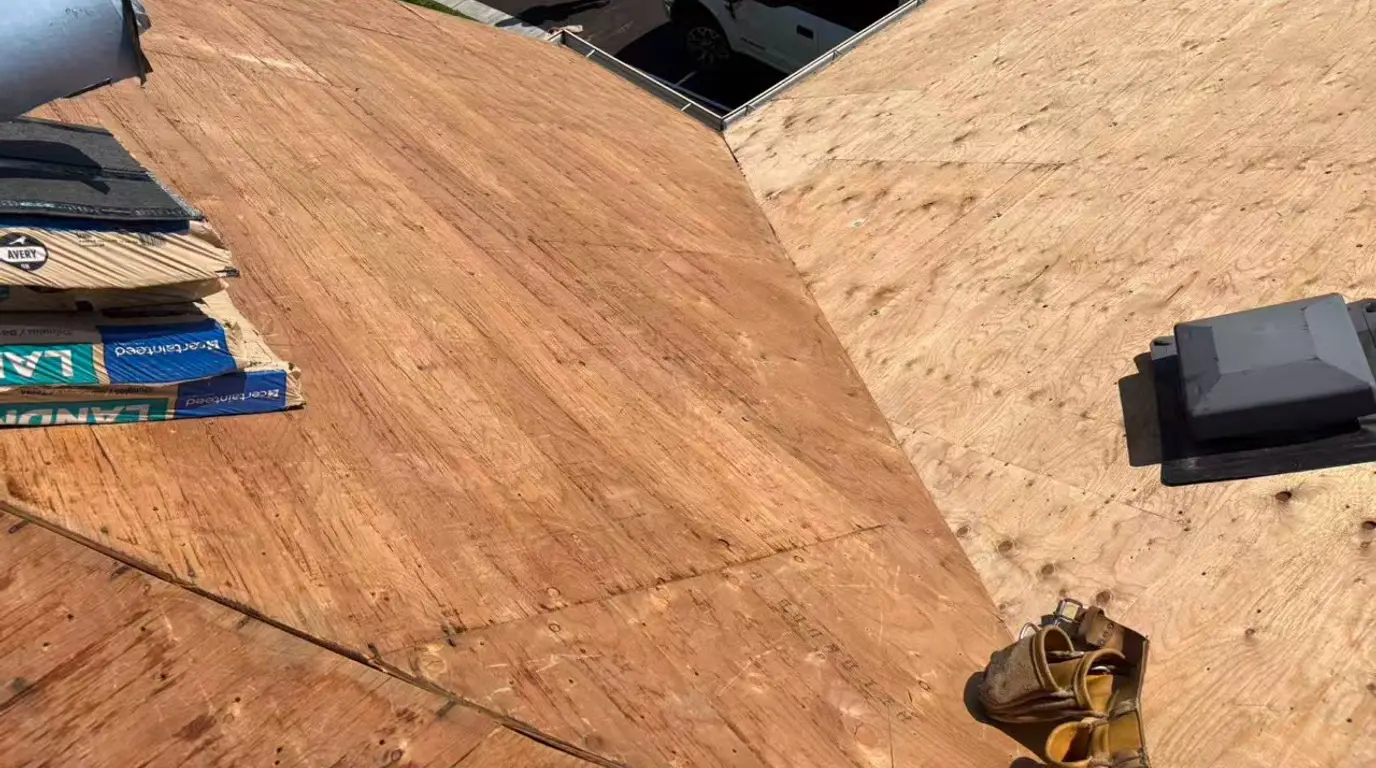 Fresh plywood decking with nailer and shingle bundle, part way through re-sheathing the roof